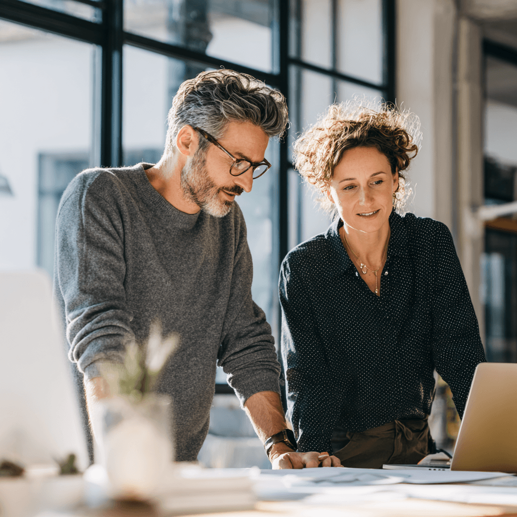 Two professionals reviewing work together at a modern desk